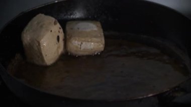Sıcak tavadan yağlı ve çıtır çıtır kızarmış altın sarısı tofu kaldırılıyor. Buhar köpüren yağdan çıkarılıp kızarmanın son adımını yakalarken yükselir. 4K 