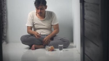 Sefil bir adam yemek için pirinç paketi açıyor, beyaz bir arka planda izole edilmiş. Sahne, açlık, hayatta kalma ve temel gıda hazırlığını sembolize eden basitlik ve günlük mücadeleyi gösteriyor. 4K görüntüsü