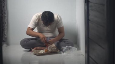 Asyalı bir adam yemeğine kırmızı biber sosu ekliyor ve yemeği için baharatlı bir tat yaratıyor. Sahne günlük yeme alışkanlıklarını, geleneksel mutfağı ve basit yiyeceklerin zevkini yansıtıyor. Şu an. 4K