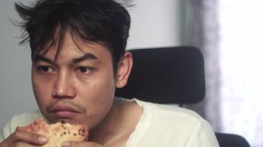 Asyalı bir adam iştahla ekmek çiğniyor, doğal ve anlamlı bir yemek anı yaşıyor. Görüntüler insani duyguları, iştahı ve günlük aktiviteleri vurguluyor. Stok görüntüleri için uygun