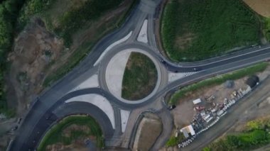 Yuvarlak kavşağın üstünden geçen arabaların kuş bakışı görüntüsü. Şehir trafiğini kolaylaştıracak yeni yol inşaatı