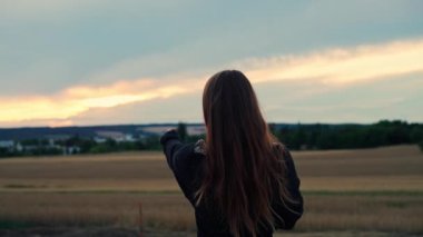Uzak bir yeri işaret eden ve kameraya bakan güzel bir kızın orta ölçekli fotoğrafı.