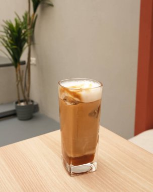 Buzlu karamel macchiato. Ahşap masada cam içinde kahve.