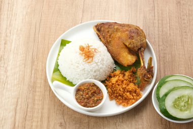 Bebek Goreng Kremes, acı sos (sambal) ve salatalık ile servis edilir. Endonezya yemekleri