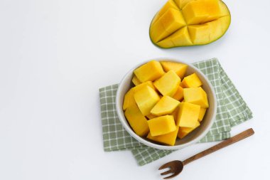 Tahta arka planda beyaz kasede servis edilen dilimlenmiş taze mango küpleri. Boşluğu kopyala
