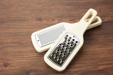 Stainless steel kitchen grater on wooden table clipart