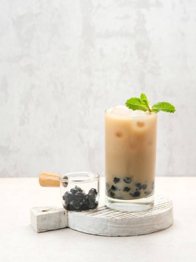 Buzlu ve nane yapraklı uzun bir bardakta kahverengi şeker şurubuyla boba sütü çayı.