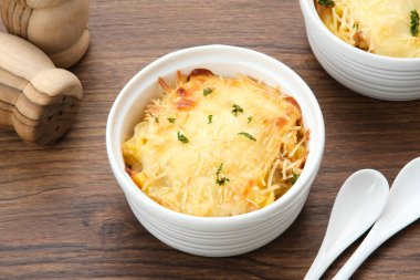 Parmesanlı ve otlu beyaz bir kasede fırında makarna ve peynir.