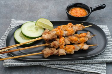 Sate Taichan, kızarmış tavuk, fıstık sosu ve soya sosu olmadan. Tabakta sambal (acılı sos) ile servis edilir.). 