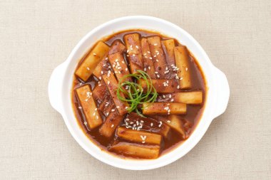 Tteokbokki or Topokki , stir fried rice cake stick, popular Korean street food with spicy gochujang sauce and sesame seed.  clipart