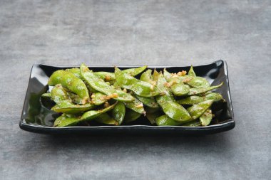 Kızarmış Edamame 'yi sarımsak ve biber tozuyla karıştır.