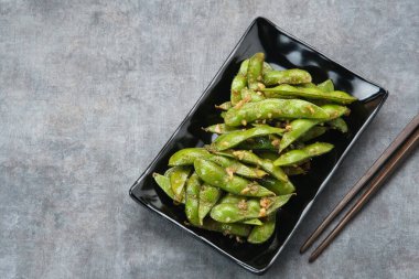 Kızarmış Edamame 'yi sarımsak ve biber tozuyla karıştır.