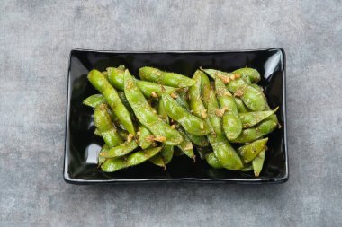 Kızarmış Edamame 'yi sarımsak ve biber tozuyla karıştır.