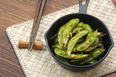 Kızarmış Edamame 'yi sarımsak ve biber tozuyla karıştır.