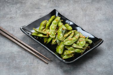 Kızarmış Edamame 'yi sarımsak ve biber tozuyla karıştır.