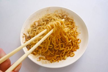 Tabakta baharatlı hazır şehriye yemek için yemek çubuğu tutan el.