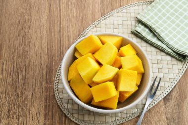 Fresh and ripe mango fruit slice on wooden bowl clipart