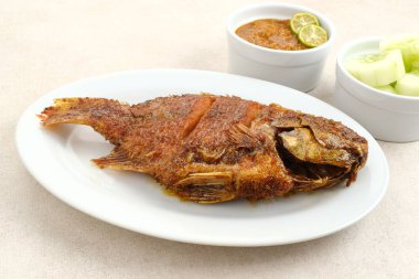 Ballı ve soya soslu ızgara Tilapia veya Ikan Nila Bakar. Beyaz tabakta sambal (acılı sos) ve salatalık ile servis edilir.