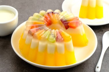 Meyve soslu lezzetli mango sütlü puding. Beyaz tabakta servis edilir.