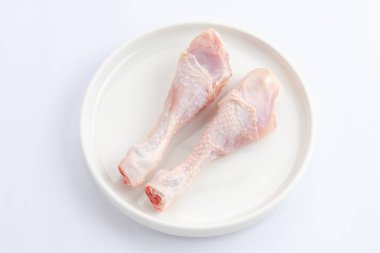 Pişirme hazırlıkları için beyaz tabakta çiğ tavuk butları.