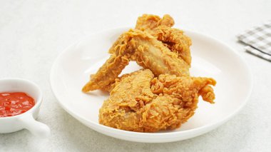 Beyaz tabakta acılı sosla servis edilen kızarmış tavuk kanatları.