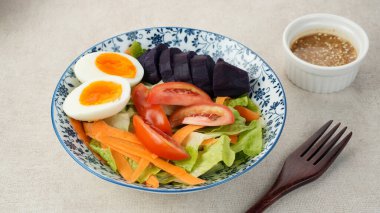Sağlıklı salata kasesi, sebze havucu, marul, domates, tatlı patates ve susam soslu yumurta karışımı.