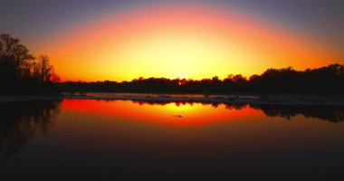 Nehirde gün batımını rahatlatıyor.