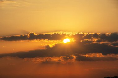 Yaz gün batımı. Batan güneşin bir bulutlu gökyüzü arka planda.