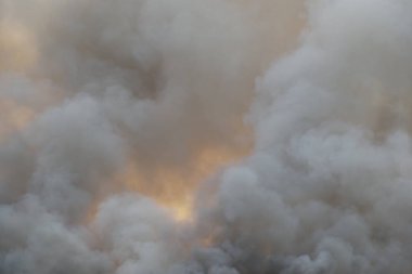 Beyaz ve siyah duman, kırmızı tozlu duman arka planda çimen tarlalarında yangın, gökyüzüne siyah ve beyaz duman. Yakından büyük bir yangın var. Hava konseptinde kirlilik. Savaştan çıkan dumanı tüttürmek için ateş.
