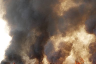 Siyah duman deseni, çimen tarlalarında yanan kırmızı ateş alevi, ormanlar ve gökyüzüne doğru siyah beyaz duman. Yakından büyük bir yangın var. Hava konseptinde kirlilik. Vahşi ateş, dünyadaki çalıları kirletiyor..