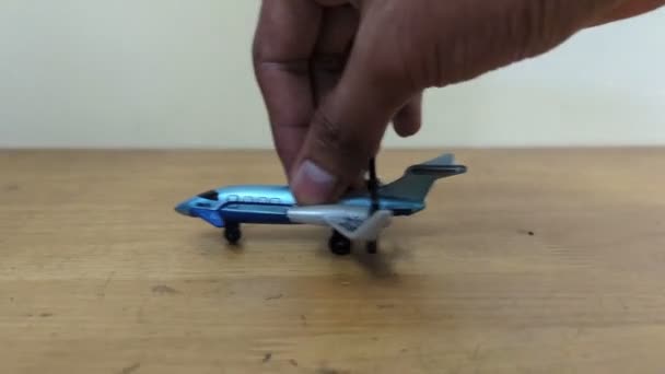 一个人玩蓝色的飞机玩具 用手在桌子上来回跑来跑去 — 图库视频影像