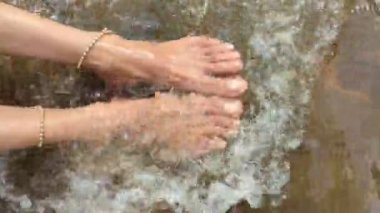 Halhalı olan bir kadının ayakları nehirde akan suyla yıkanır. 