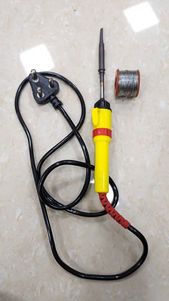 an electric soldering tool with plug and solder metal wire on the floor used by students and electricians in the lab