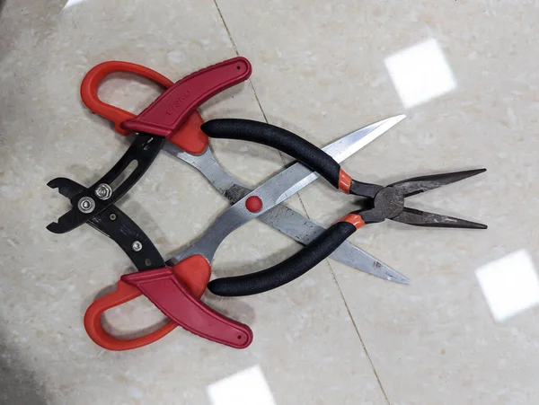 various cutting tools like scissor, cutting plier and wire stripper used in the electronics lab placed on a white floor