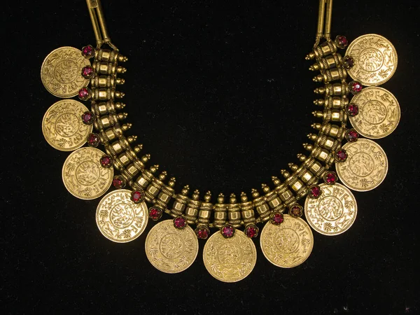 a vintage gold necklace with ornate design and detailed carvings which was used by royalty displayed on a black background