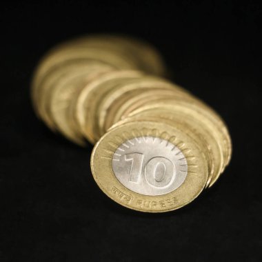 Nadir bulunan antika altın ve gümüş Hint paralarının yakın plan çekimi. 10 rupi, siyah bir arkaplanda izole edilmiş eğri bir sıra halinde dizilmiş.