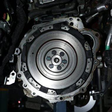 metallic flywheel mount on the transmission assembly of a vehicle in a auto repair shop in closeup clipart