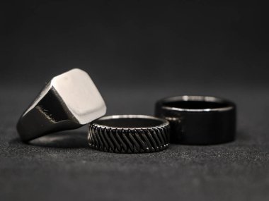 Siyah arka planda izole edilmiş bir kuyumcudan minimalist tasarımı olan metalik platin lüks yüzüklere yakın plan.