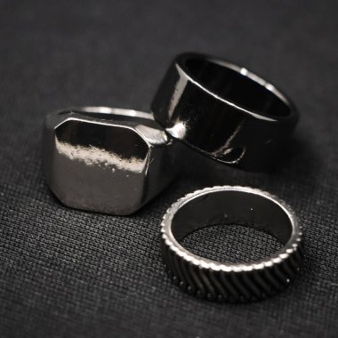 Siyah arka planda izole edilmiş bir kuyumcudan minimalist tasarımı olan metalik platin lüks yüzüklere yakın plan.