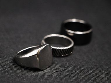 Siyah arka planda izole edilmiş bir kuyumcudan minimalist tasarımı olan metalik platin lüks yüzüklere yakın plan.