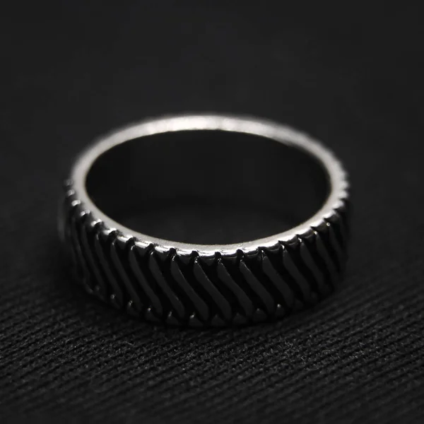 closeup shot of a circular platinum ring with a neatly cut design isolated in a black background