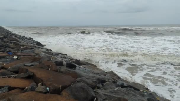 在多云的雨季里 海潮在岸上的黑岩床上冲击着并飞溅着 — 图库视频影像