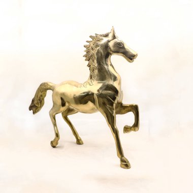 Beyaz arka planda izole edilmiş antika dekorlar satan bir hediyelik eşya dükkanından altın oyulmuş bir at aygırının lüks heykeli.