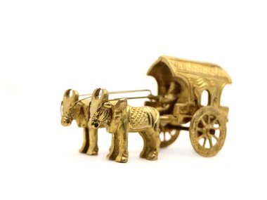 Tarihi zamanlarda köylerde beyaz bir arka plana karşı taşımacılık ve tarımda kullanılan antika bir öküz arabasının karmaşık bir şekilde imal edilmiş altın modeli.