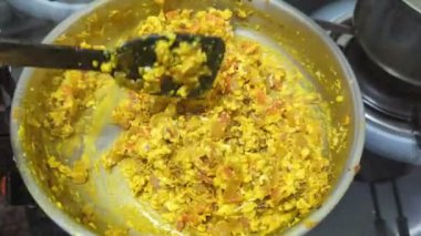 Çelik bir tavada lezzetli yumurta burji masala yapan bir kadın, mutfakta yemek malzemelerini karıştırıyor ve karıştırıyor.