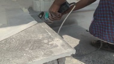 İnşaat alanından seramik kesme makinesiyle granit kesen bir işçinin eli.