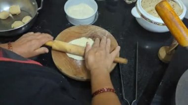 Mutfakta, yuvarlak hamuru yuvarlayan bir kadının eli yuvarlak yuvarlak yuvarlak ekmek roti hazırlamak için ahşap silindirli ve tahtadan yapılmış.