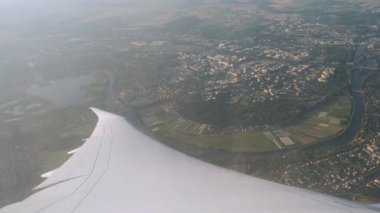 Uçak gökyüzünden görüldüğü gibi şehir üzerinde dönerken yolcu kanadının penceresinden iniş görüntüsü.