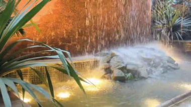 Yapay bir şelale çeşmesinden dekoratif havuza akan su, lüks bir deneyimin göstergesidir.