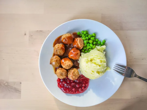 A traditional dish of Swedish regional cuisine - meatballs with mashed potatoes are served with lingonberry sauce and green peas.